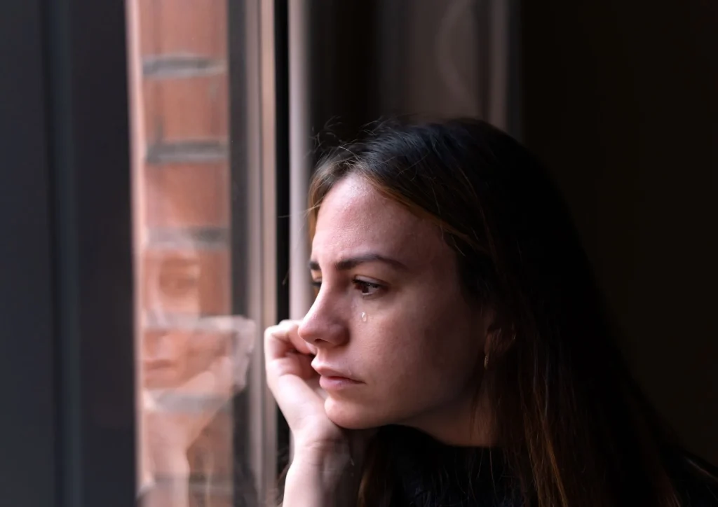 woman looking out window reflection sad