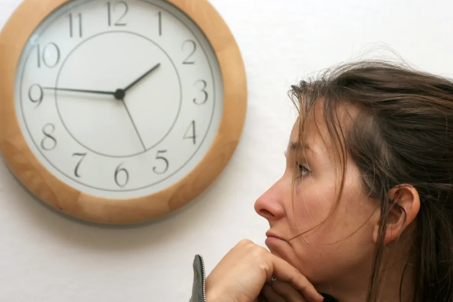 Frau sitzt allein, nachdenklich mit Uhr an der Wand